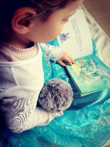 Enfant qui lit l'histoire illustrée des Crodoux avec sa peluche Tidoux toute douce